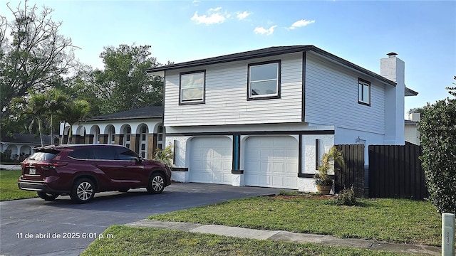 view of front of house featuring an attached garage, a chimney, aphalt driveway, and fence