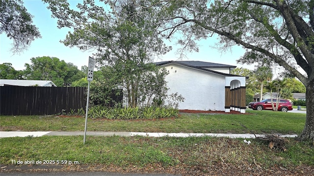 view of home's exterior featuring stucco siding, fence, and a lawn