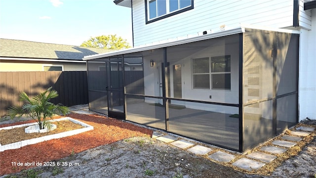 exterior space with fence, a sunroom, and concrete block siding