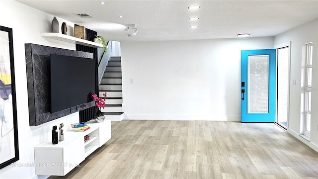 unfurnished living room with stairs, light wood finished floors, and recessed lighting