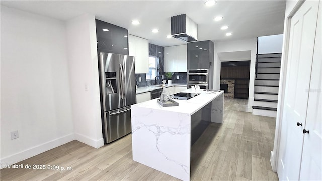 kitchen featuring a kitchen island with sink, baseboards, light wood-style floors, modern cabinets, and black appliances