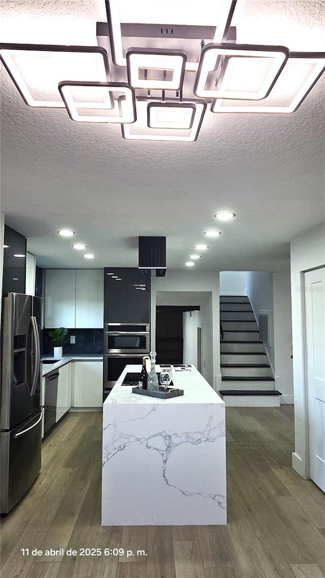 kitchen featuring a textured ceiling, fridge with ice dispenser, dishwashing machine, and dark wood-style floors