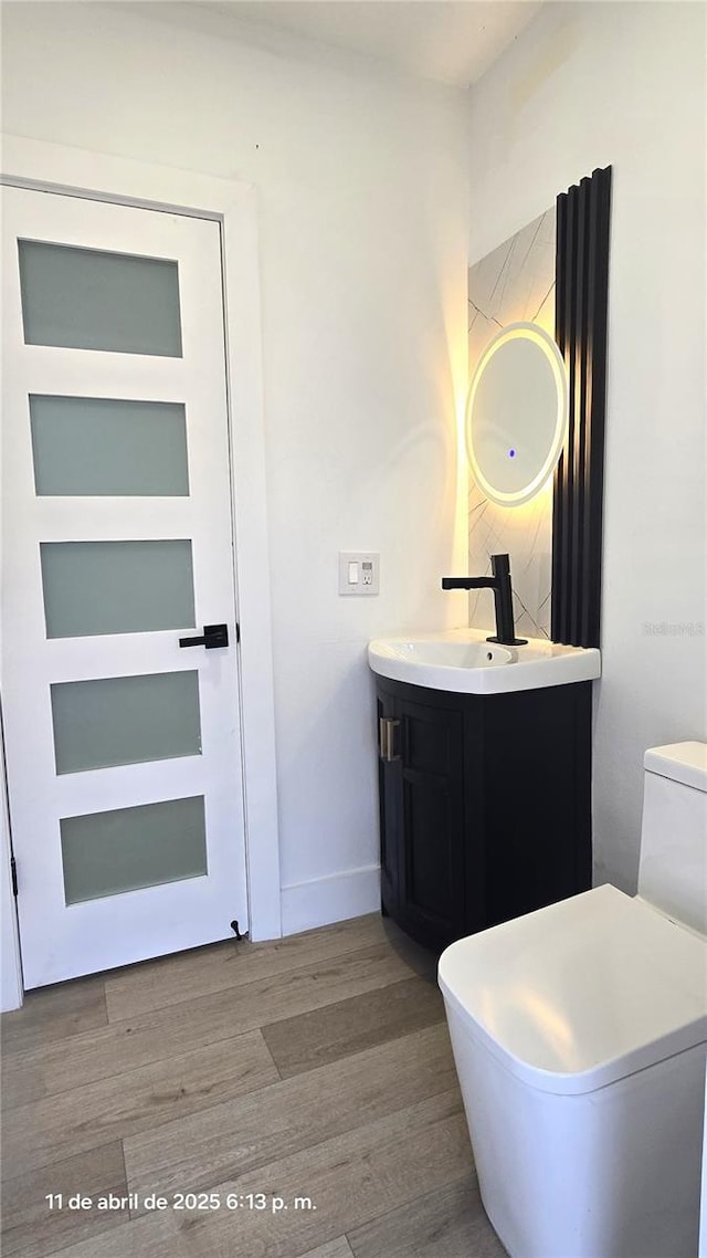 bathroom featuring baseboards, wood finished floors, and vanity