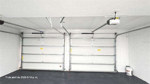 garage featuring concrete block wall and a garage door opener