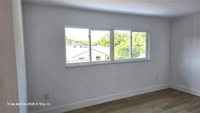 spare room with wood finished floors and baseboards