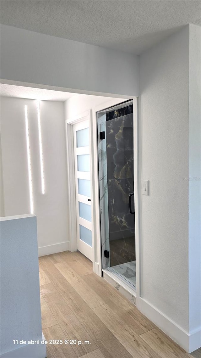 interior space with baseboards, wood finished floors, and a textured ceiling