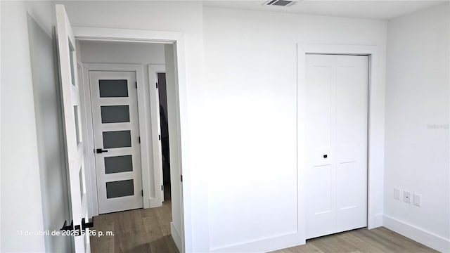 interior space featuring baseboards, wood finished floors, and visible vents