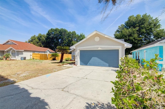 view of front of home with concrete driveway, a front lawn, fence, a garage, and stucco siding