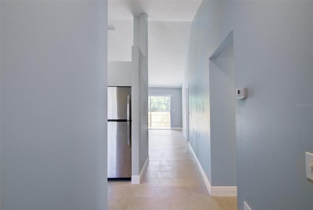 hallway featuring baseboards and light tile patterned flooring