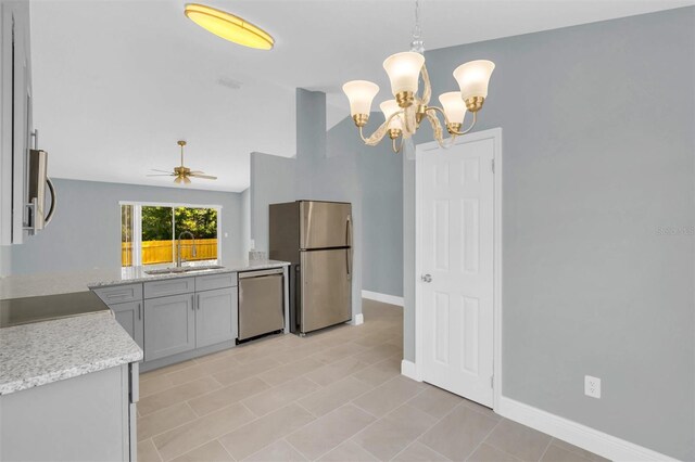 kitchen featuring a sink, lofted ceiling, ceiling fan with notable chandelier, baseboards, and appliances with stainless steel finishes