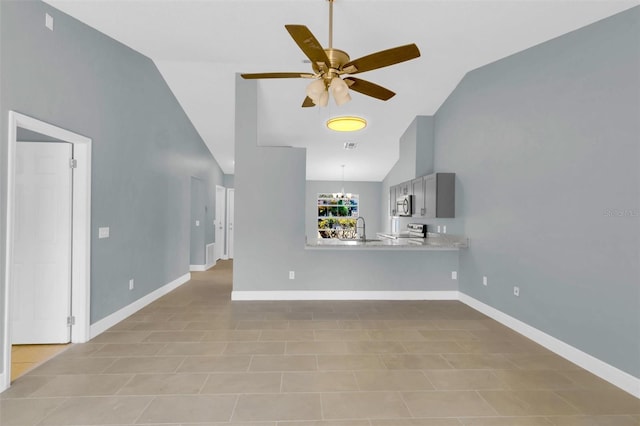 unfurnished living room featuring ceiling fan with notable chandelier, baseboards, a sink, and high vaulted ceiling