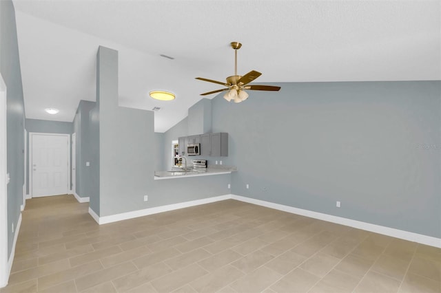 unfurnished living room with vaulted ceiling, baseboards, and ceiling fan