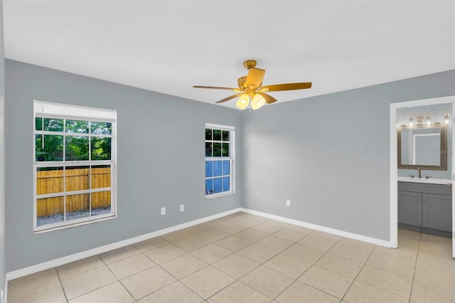 unfurnished bedroom with a sink, connected bathroom, light tile patterned floors, ceiling fan, and baseboards