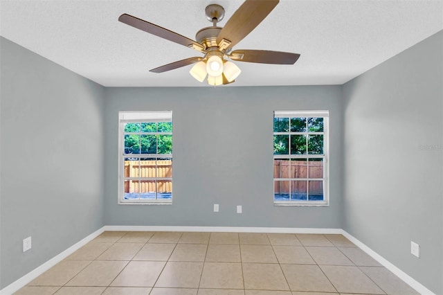 unfurnished room with light tile patterned flooring, a textured ceiling, a ceiling fan, and baseboards