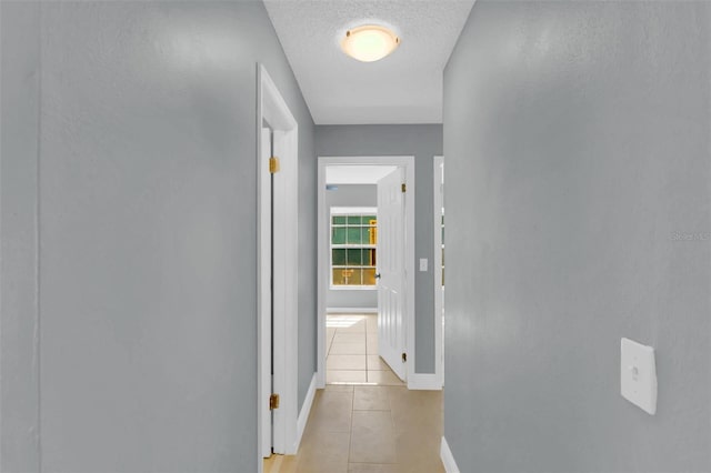 hallway with baseboards and light tile patterned floors