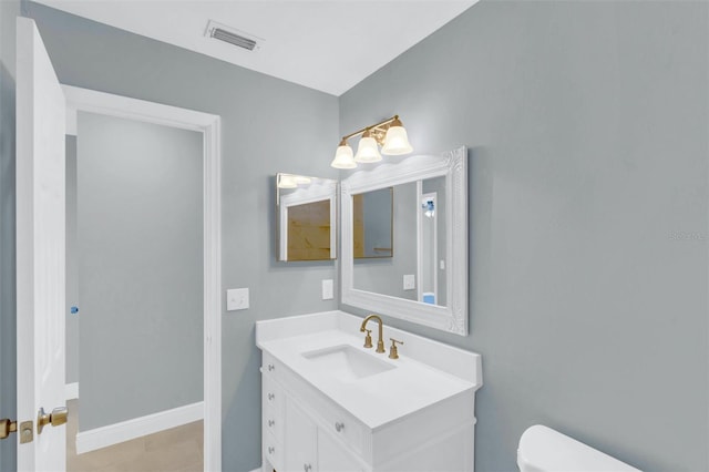 bathroom featuring toilet, vanity, visible vents, and baseboards