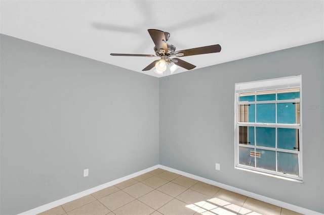unfurnished room with a ceiling fan, baseboards, and light tile patterned floors