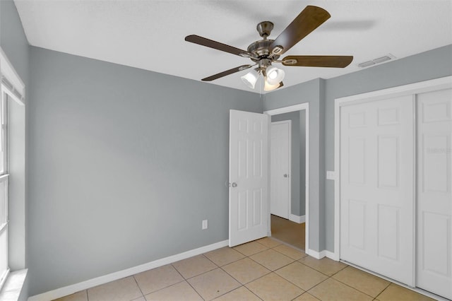 unfurnished bedroom featuring light tile patterned floors, baseboards, visible vents, and a closet