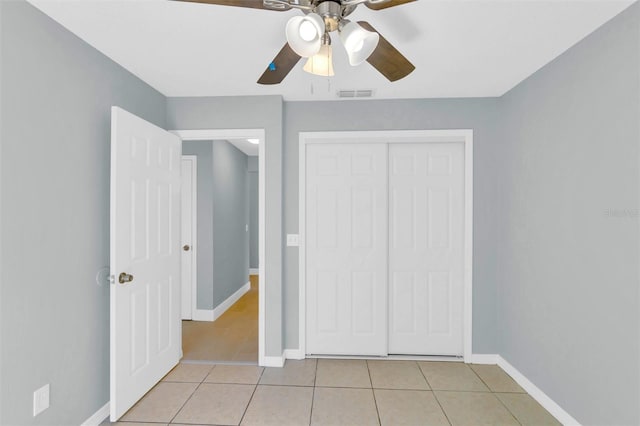 unfurnished bedroom featuring a ceiling fan, a closet, light tile patterned floors, baseboards, and visible vents