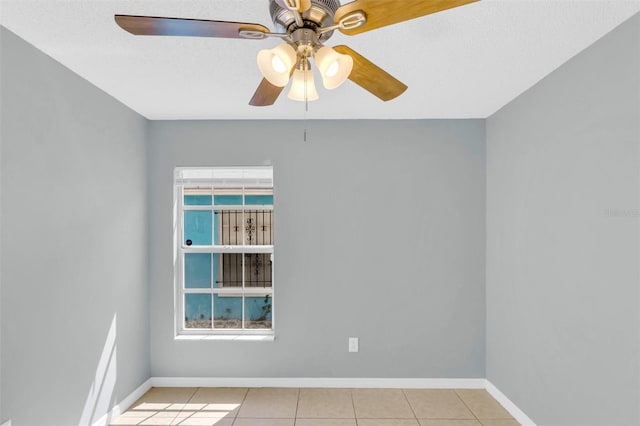 empty room featuring baseboards, ceiling fan, and light tile patterned flooring