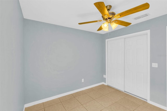 unfurnished bedroom featuring visible vents, light tile patterned floors, a closet, baseboards, and ceiling fan