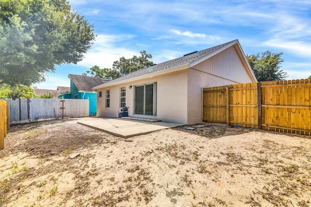 rear view of property featuring a fenced backyard, roof with shingles, a patio, and stucco siding