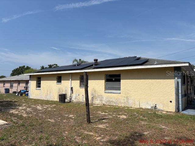 2117 Lemon St, Haines City, FL 33844 - view of side of home featuring stucco siding, roof mounted solar panels, and cooling unit