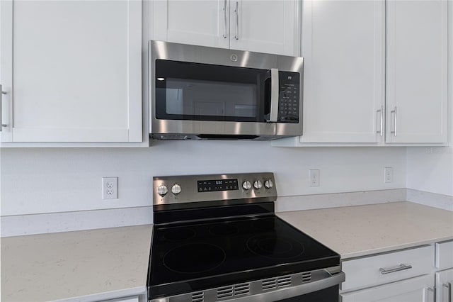 808 Lake Dell Rd, Dundee, FL 33838 - kitchen featuring appliances with stainless steel finishes, white cabinets, and light stone counters