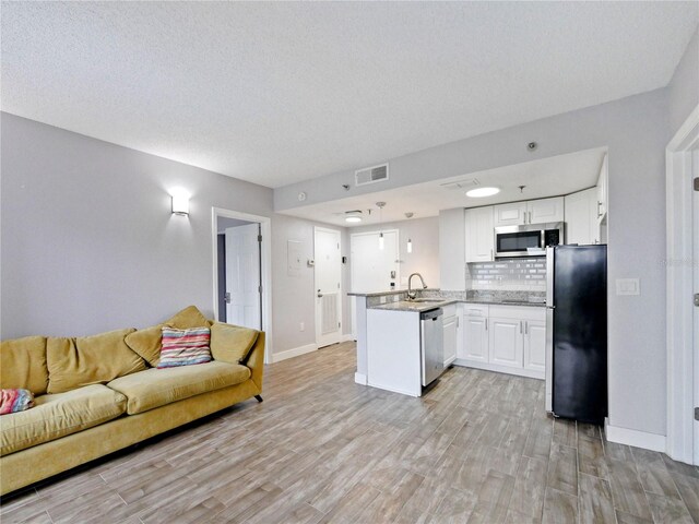 6165 Carrier Dr Unit 1603, Orlando, FL 32819 - kitchen featuring stainless steel appliances, a peninsula, open floor plan, light wood-type flooring, and tasteful backsplash