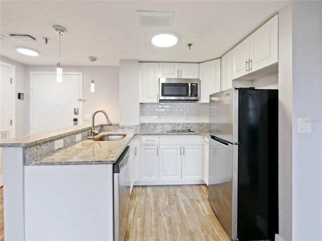 6165 Carrier Dr Unit 1603, Orlando, FL 32819 - kitchen with stainless steel appliances, a sink, light wood-type flooring, a peninsula, and white cabinets