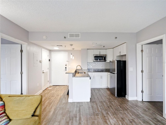 6165 Carrier Dr Unit 1603, Orlando, FL 32819 - kitchen with appliances with stainless steel finishes, a peninsula, a sink, light wood-style flooring, and white cabinetry
