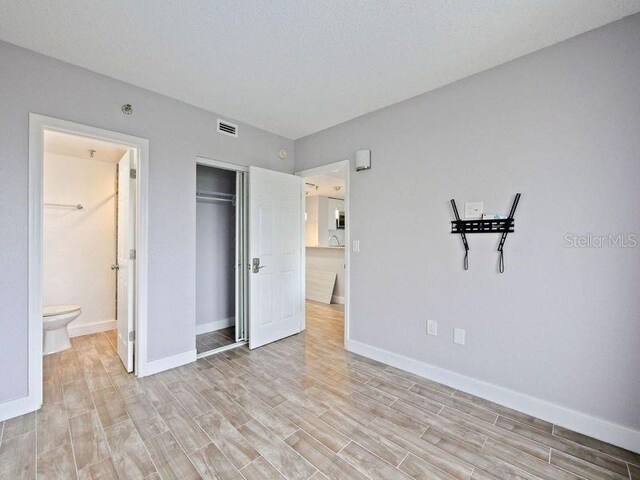 6165 Carrier Dr Unit 1603, Orlando, FL 32819 - unfurnished bedroom with light wood-style flooring, baseboards, a closet, and ensuite bathroom