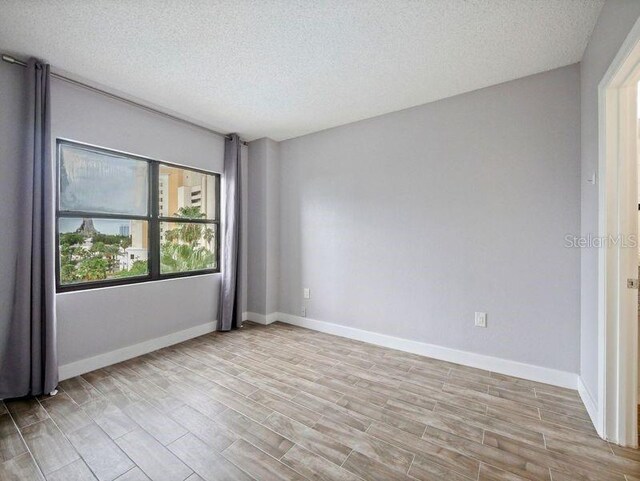 6165 Carrier Dr Unit 1603, Orlando, FL 32819 - unfurnished room featuring a textured ceiling, light wood finished floors, and baseboards
