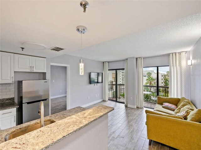 6165 Carrier Dr Unit 1603, Orlando, FL 32819 - kitchen with freestanding refrigerator, open floor plan, a sink, and light stone counters