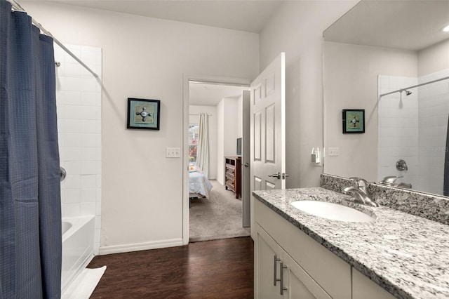 bathroom featuring wood finished floors, ensuite bathroom, baseboards, shower / bathtub combination with curtain, and vanity