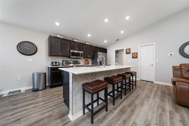2059 Dexter St, Haines City, FL 33844 - kitchen with light wood finished floors, a kitchen breakfast bar, stainless steel appliances, and a kitchen island with sink