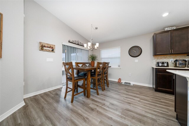 2059 Dexter St, Haines City, FL 33844 - dining space with light wood-type flooring, vaulted ceiling, baseboards, and an inviting chandelier