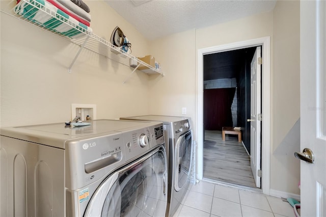 997 Lake Berkley Dr, Kissimmee, FL 34746 - laundry area featuring washing machine and clothes dryer, a textured ceiling, light tile patterned flooring, baseboards, and laundry area