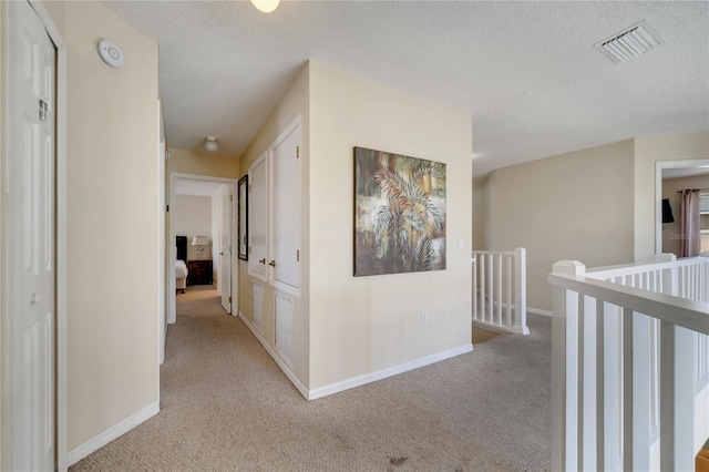 997 Lake Berkley Dr, Kissimmee, FL 34746 - hallway with an upstairs landing, a textured ceiling, light carpet, baseboards, and visible vents