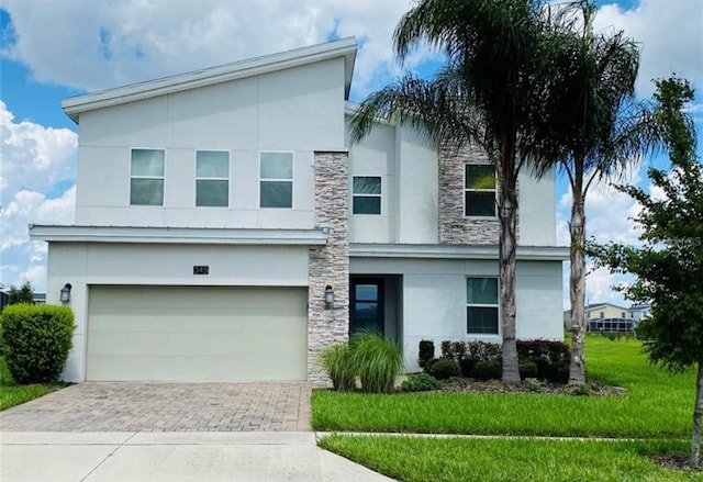 345 Ocean Course Ave, Davenport, FL 33896 - modern home featuring stucco siding, an attached garage, decorative driveway, and stone siding