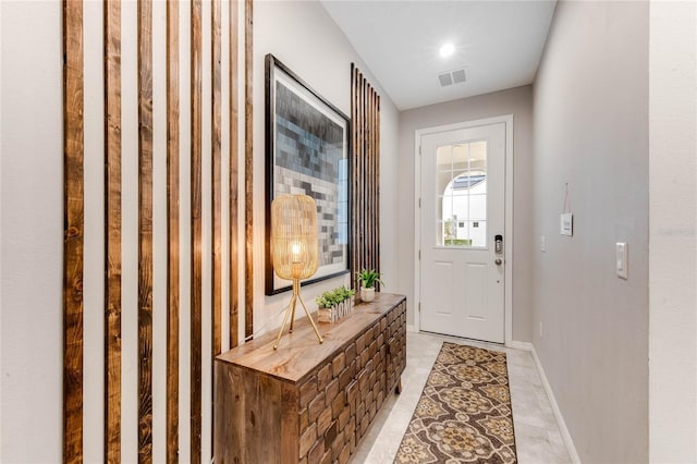 doorway with baseboards, visible vents, and light tile patterned floors