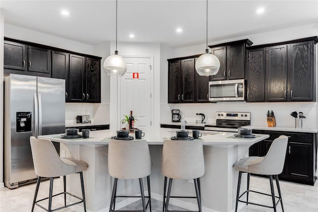 kitchen with stainless steel appliances, light countertops, pendant lighting, tasteful backsplash, and a breakfast bar area