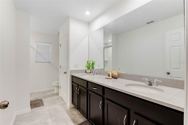 bathroom featuring visible vents, a sink, double vanity, and toilet