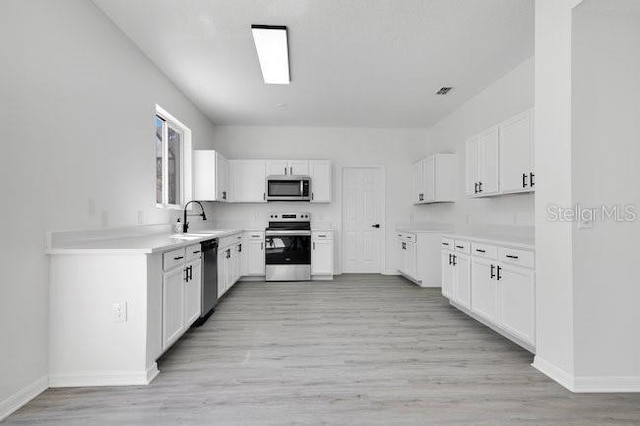 227 Sand Ridge Dr, Davenport, FL 33896 - kitchen featuring light wood finished floors, baseboards, white cabinets, and appliances with stainless steel finishes