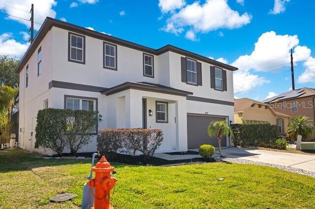 227 Sand Ridge Dr, Davenport, FL 33896 - traditional home featuring a front lawn, an attached garage, concrete driveway, and stucco siding
