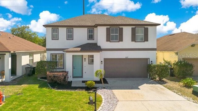 227 Sand Ridge Dr, Davenport, FL 33896 - traditional home featuring a garage, concrete driveway, a front lawn, and stucco siding