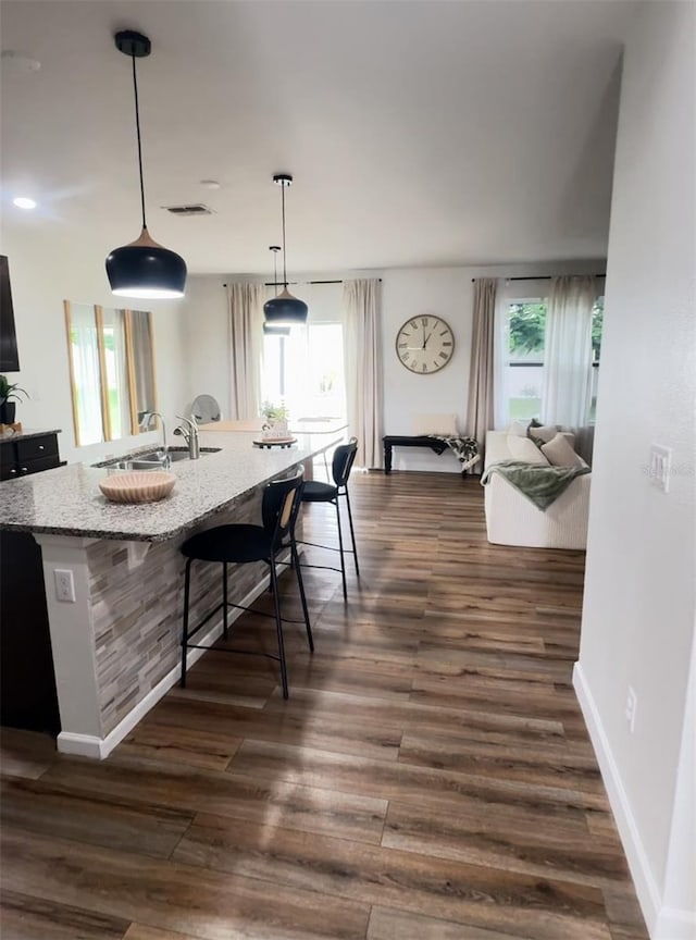 9016 Pyrus St, Kissimmee, FL 34747 - kitchen with a sink, a breakfast bar area, light stone countertops, a spacious island, and dark wood finished floors