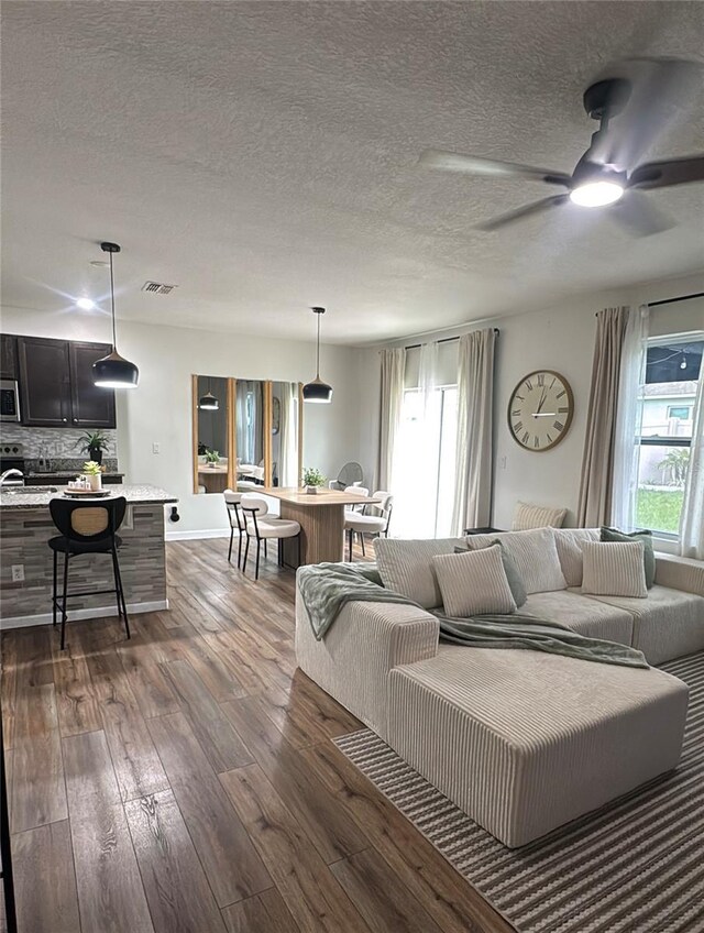 9016 Pyrus St, Kissimmee, FL 34747 - living area with dark wood-type flooring, healthy amount of natural light, ceiling fan, and a textured ceiling
