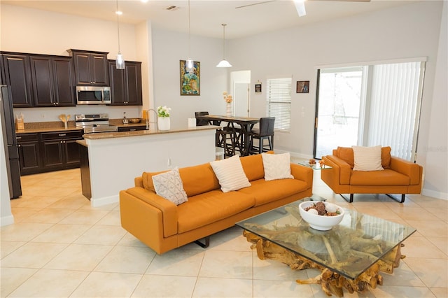 living room with a ceiling fan, baseboards, visible vents, and light tile patterned floors