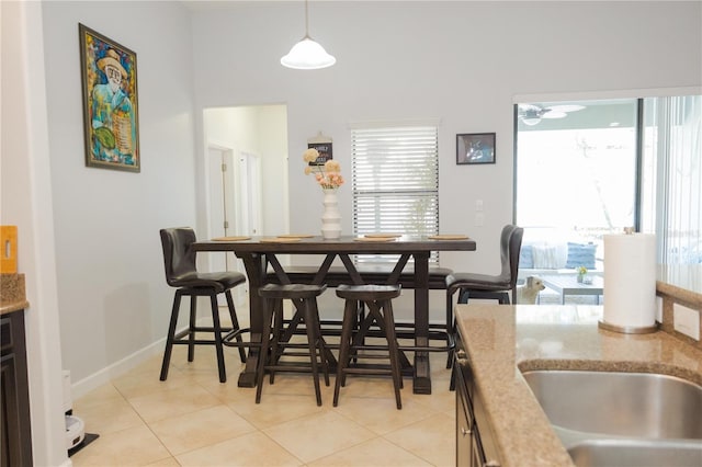 dining space featuring light tile patterned floors, baseboards, a healthy amount of sunlight, and a towering ceiling